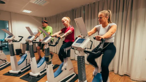 Kolme ihmistä kuntotestissä pyöräergossa