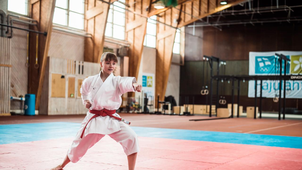Karateka harjoittelee tatamilla urheiluhallissa.