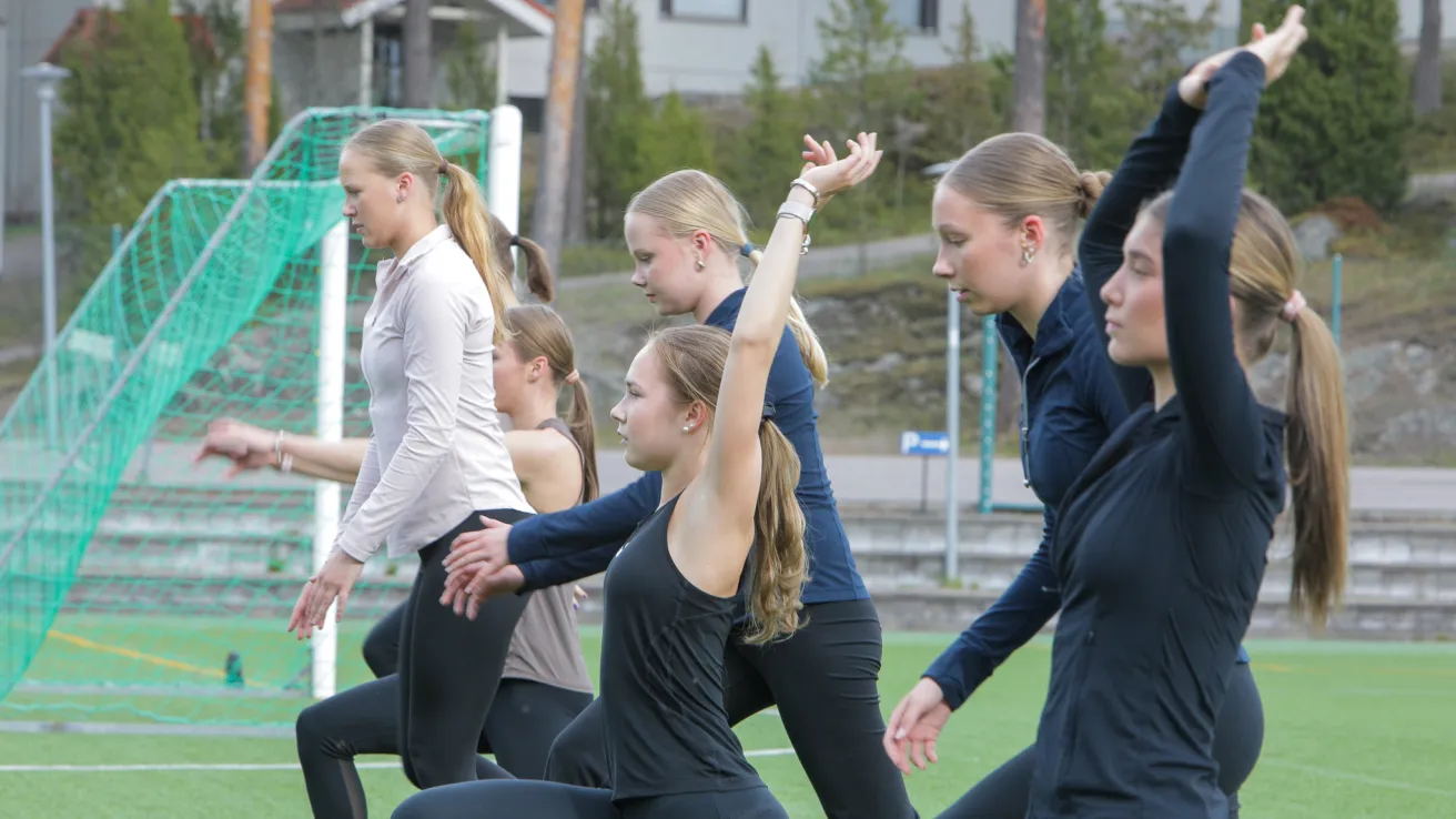 Group of people in athletic wear exercising on a field.