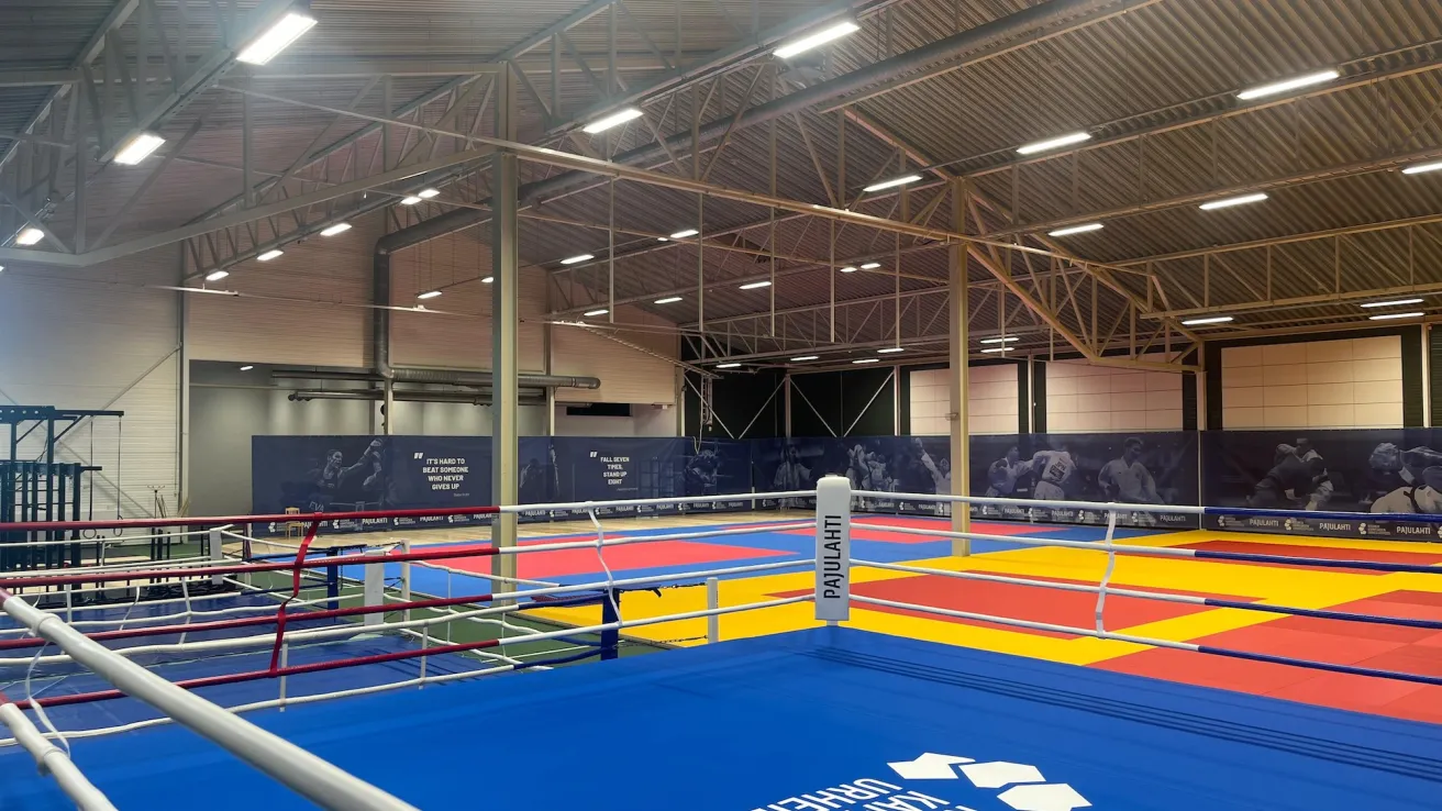 Pajulahden kamppailuareena. Sisähallissa värikkäitä voimistelumattoja ja nyrkkeilykehä, valaistus katossa.