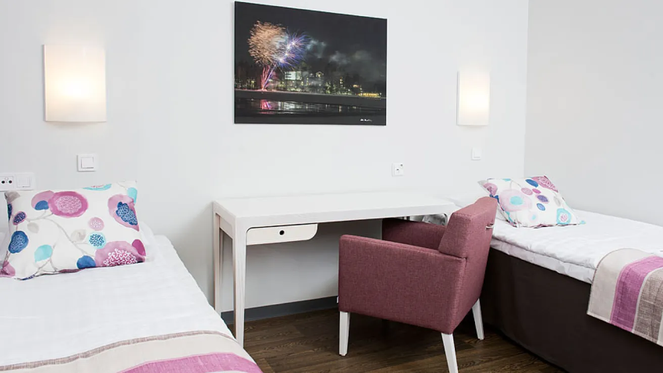 Kaksi vuodetta huoneessa, vaaleat seinät, ilotulitusvalokuva.