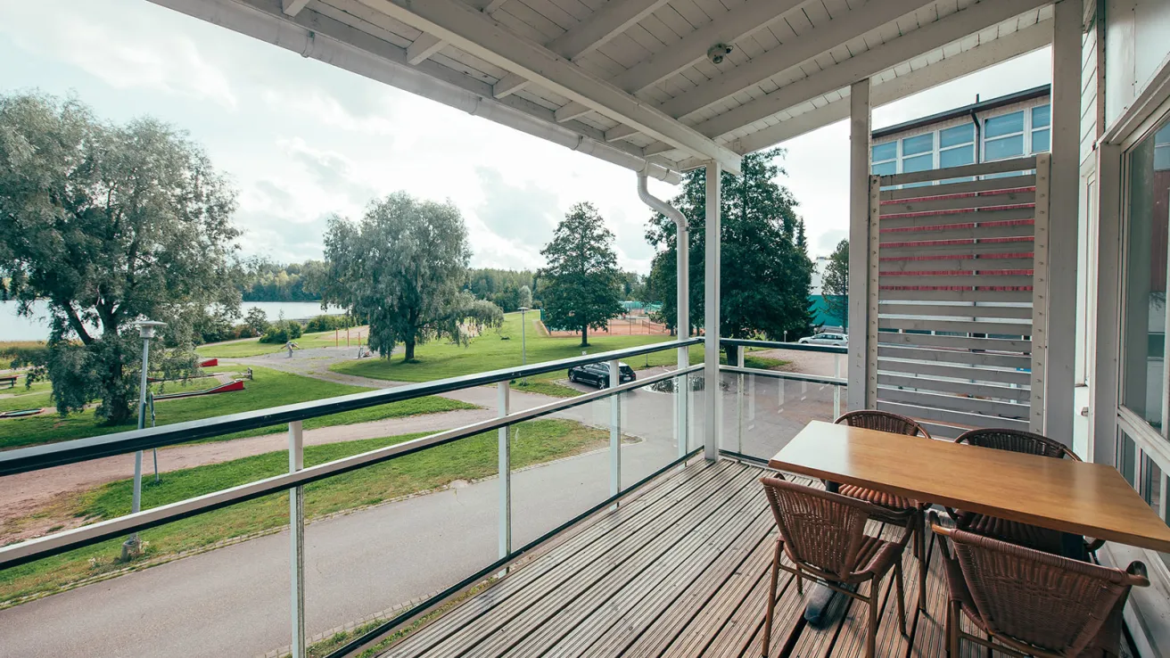 Parveke pöytineen, maisema puistoon ja järvelle.