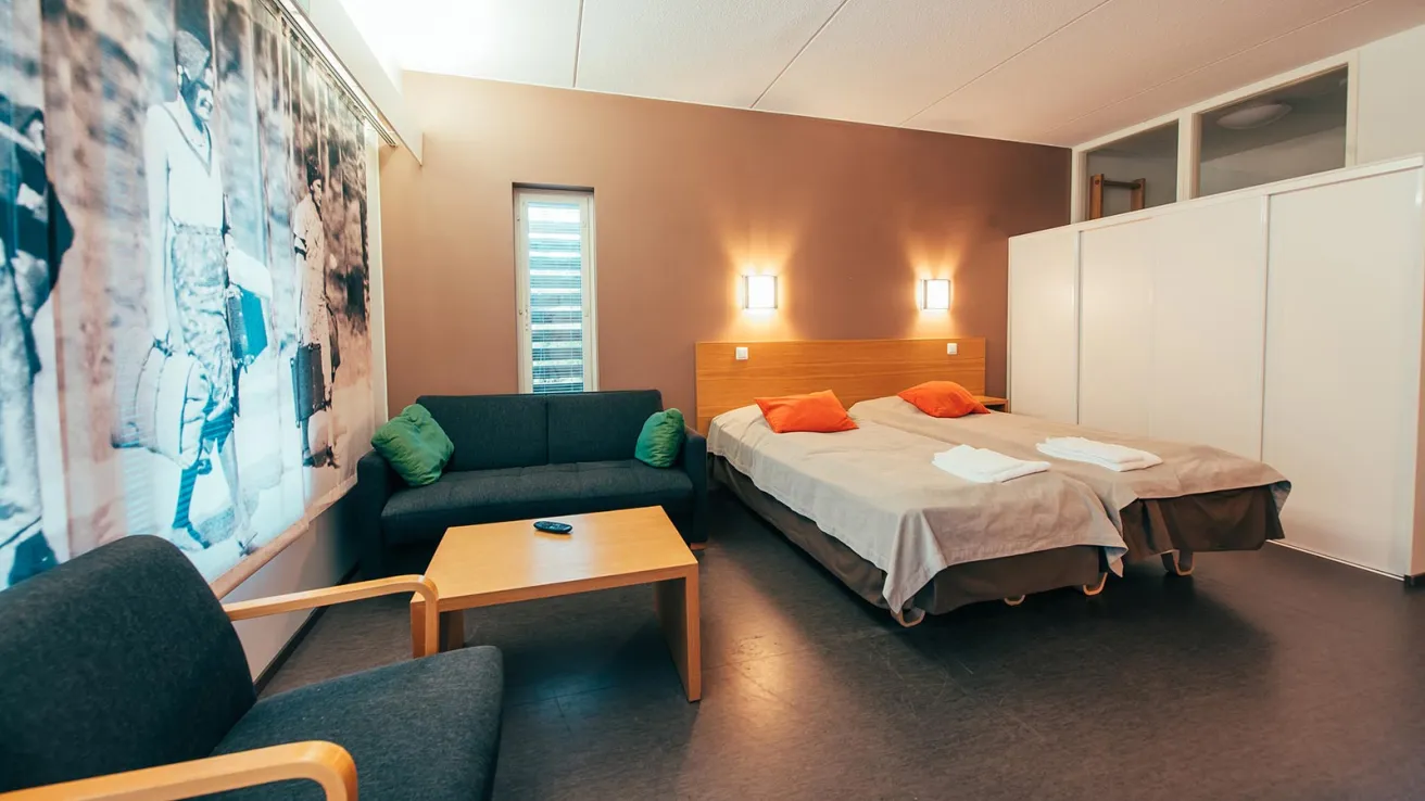 Moderni hotellihuone, jossa on parivuode, sohva ja pöytä.