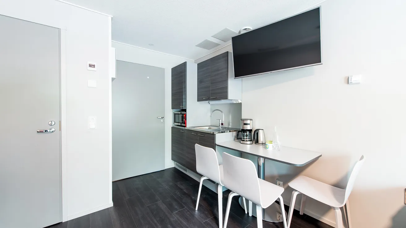 Moderni keittokomero, valkoiset ja harmaat sävyt, ruokailutila neljälle.