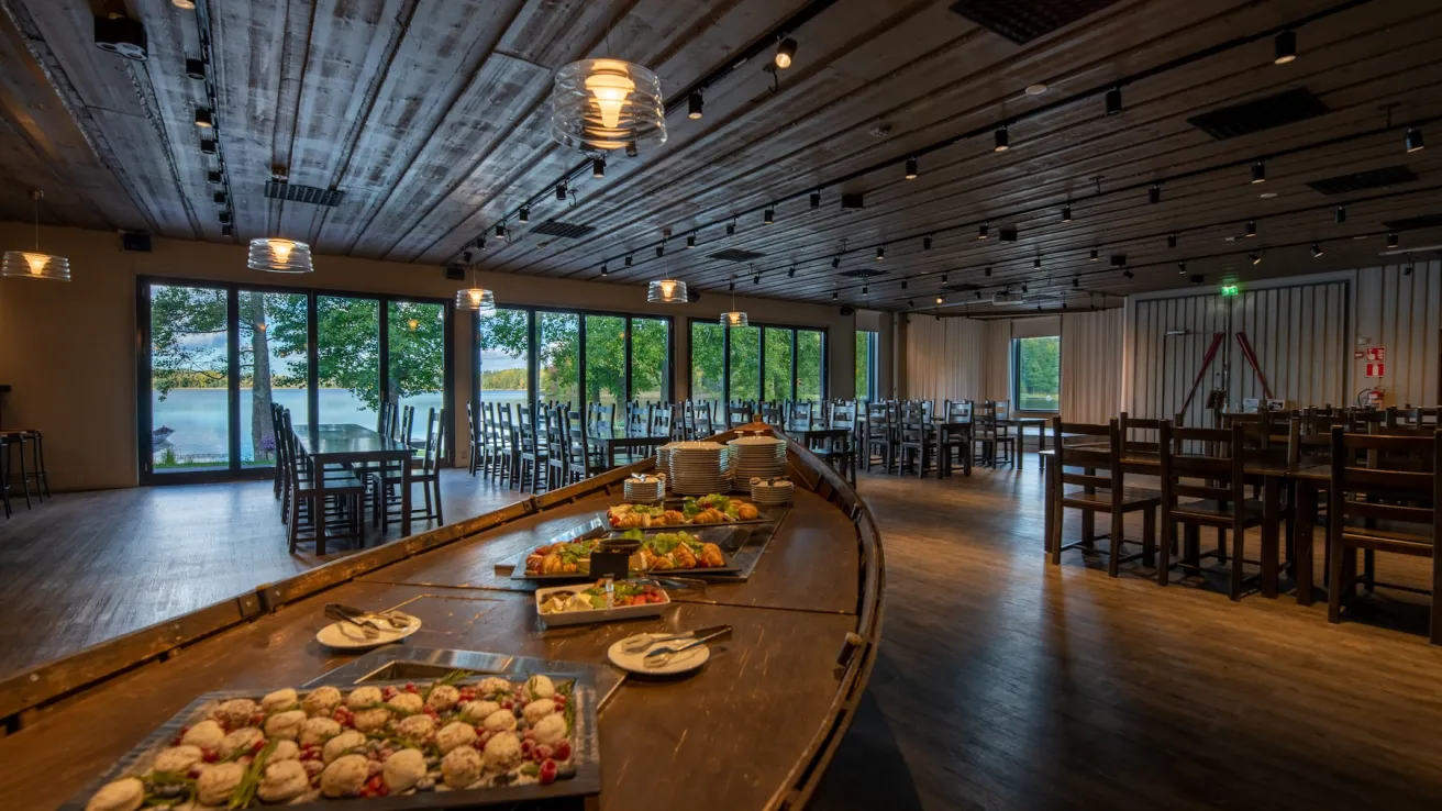 Pitkä pöytä, jolla on paljon tarjoilulautasia valaistussa juhlatilassa.