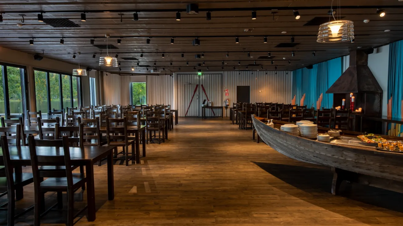 Tunnelmallinen ravintolasali, pöydät ja pitkä tarjoilupöytä.