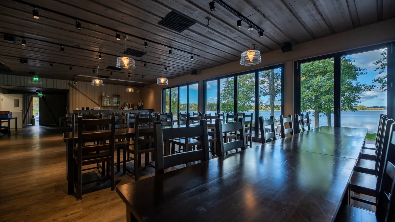 Ravintolasali järvinäköalalla, tyhjät tuolit ja pöydät.