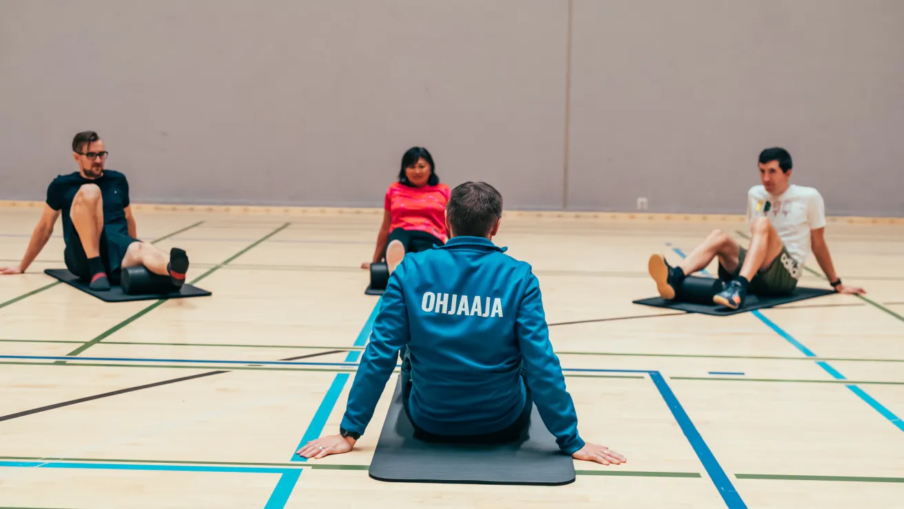 Pajulahden. liikunnanohjaaja ostuu jumppamatolla ja ohjaa ryhmälle venyttelyä.