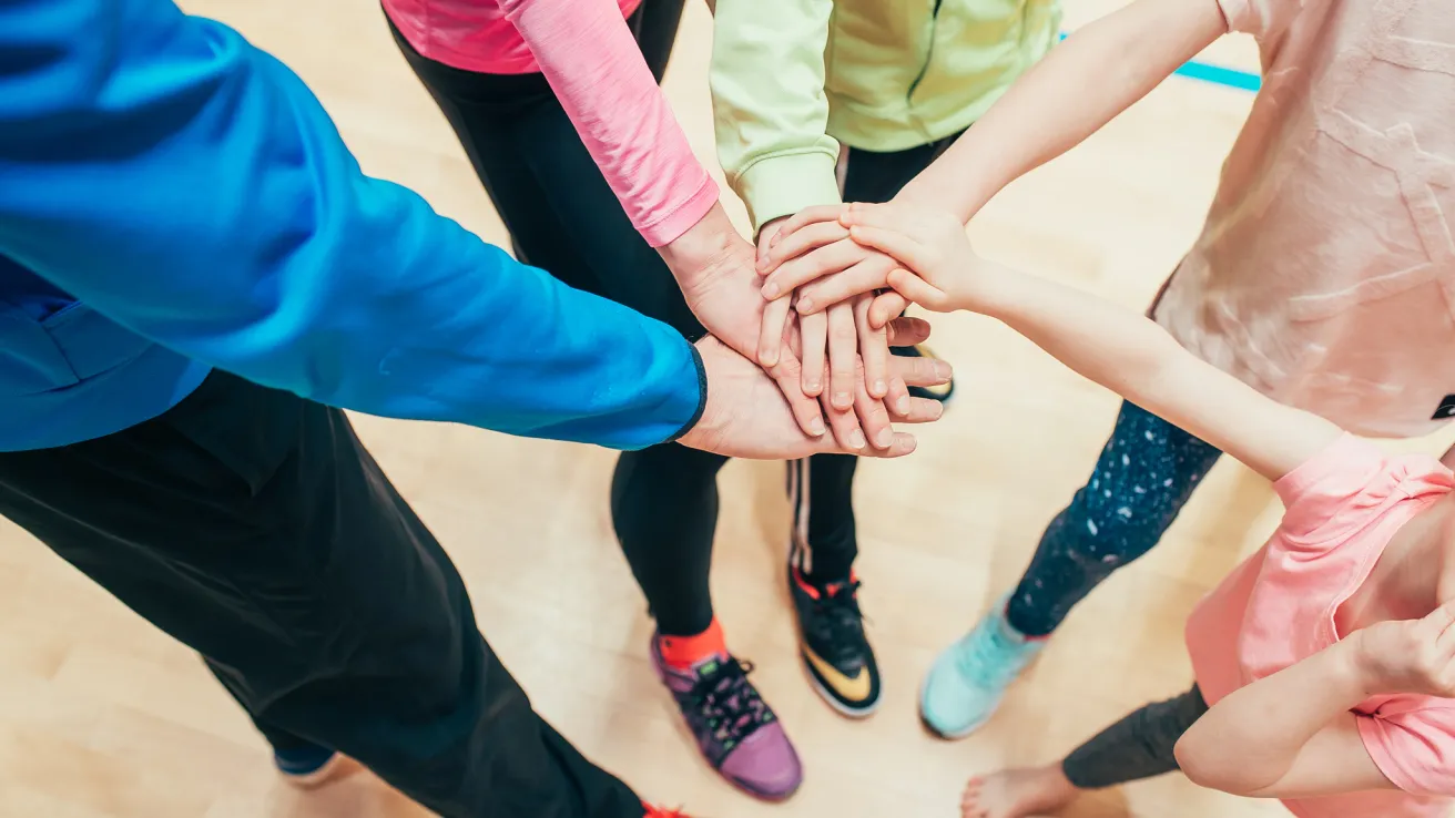 Kädet kasassa yhteishengen merkiksi, värikkäät vaatteet ja urheilujalkineet.