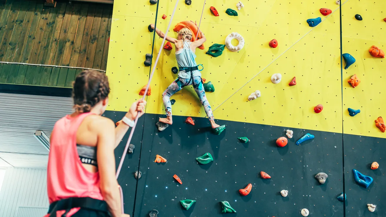 Lapsi seinäkiipeilee Pajulahden Nikula-hallissa aikuisen valvoessa alhaalla