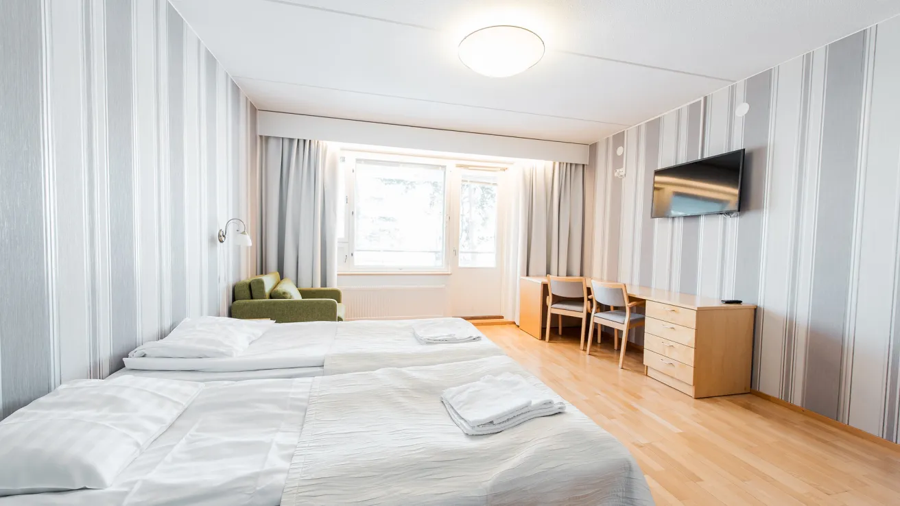 Rantapaju. Huone, jossa kaksi vuodetta, nojatuoli, pöytä ja televisio.