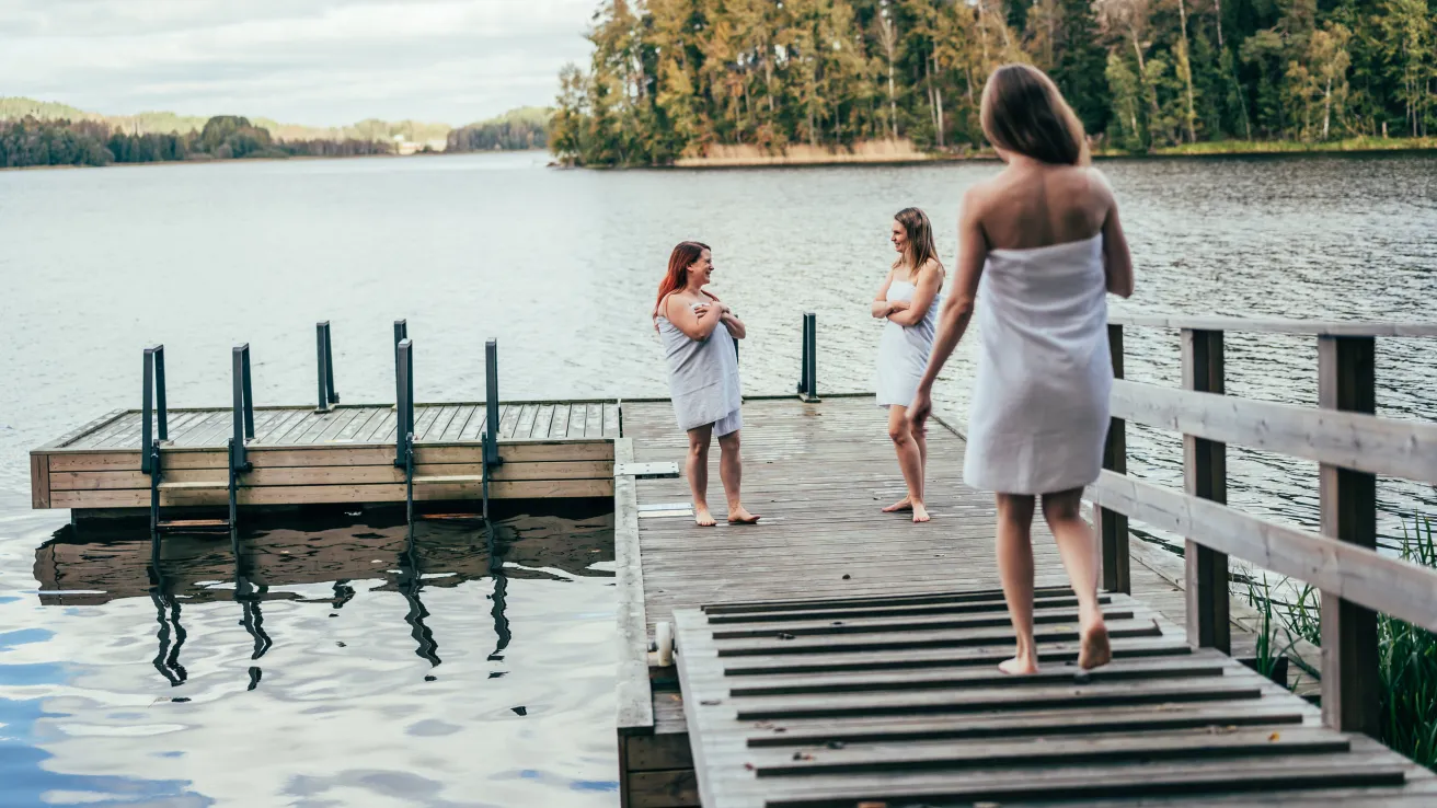 Naiset jutustelevat laiturilla pyyhkeet päällä Lohjanjärvellä..
