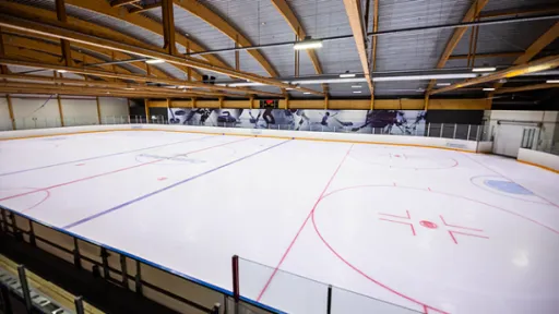 Indoor ice hockey rink with painted lines and wooden ceiling.
