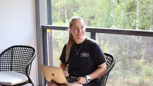 Nainen istuu terassilla ja käyttää kannettavaa tietokonetta.