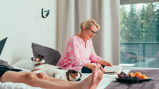 Pariskunta istuu sängyllä ja heidän välissään on kaksi pientä jackrusselinterrieriä makoilemassa.