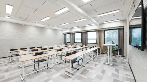 Valoisa luokkahuone, jossa on riveittäin pöytiä ja tuoleja.