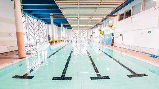 Sisäuima-allas, vaaleansininen vesi, valaistus, ja raidat pohjassa.