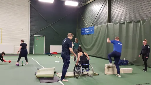 Harjoitustila, ihmiset treenaamassa, yksi henkilö pyörätuolissa.