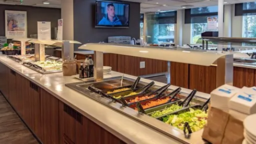 Buffet-pöytä salaattilinjoilla, ravintolasali taustalla.
