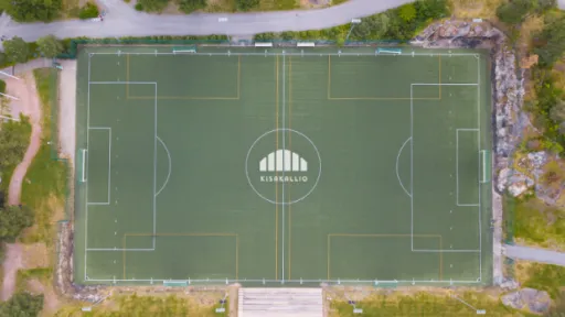 Jalkapallokenttä ylhäältä, ympärillä vihreää kasvillisuutta.