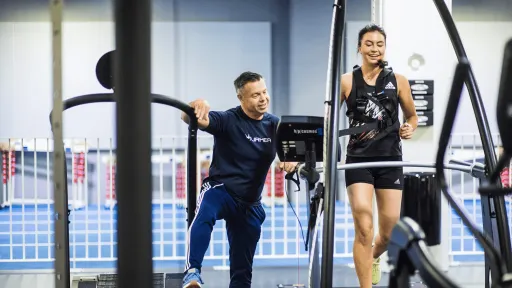 Personal trainer kannustaa naista kuntosalilla juoksemisen aikana.