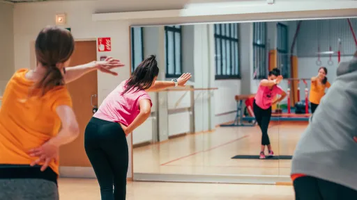 Naiset tekevät ryhmäliikuntaa kuntosalilla.