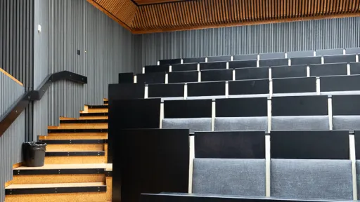 Auditorion tyhjät istuimet valkoisten katto- ja seinäpaneelien alla.