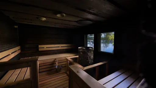 Hämyinen saunatila. Ikkunasta näkyy sininen järvi ja puita. 