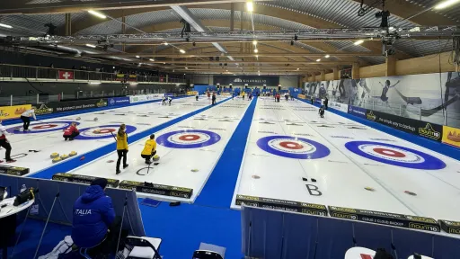Curling-halli, jossa useita kenttiä ja pelaajia.