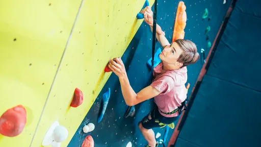 Nuori poika seinäkiipeilemässä turvaköyden varassa.