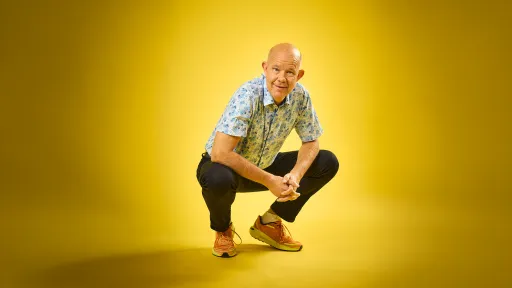 Kaj Kunnas poseeraa iloisena keltaisen taustan edessä