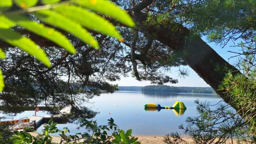 Rantamaisema, puita ja kelluva lelu järvessä.