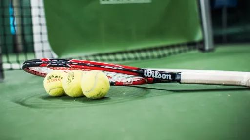 Tennis racket and three balls on a green court.