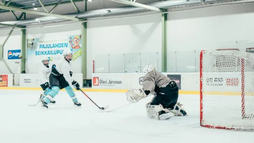 Jääkiekkoilija lähestyy maalivahtia kiekko lavassa.