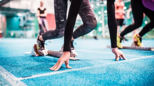 Athletes in starting blocks on an indoor blue track.