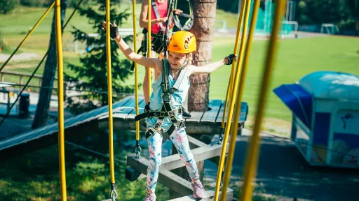 Tyttö tasapainoilee puussa olevalla esteradalla Pajulahden Seikkailupuistossa
