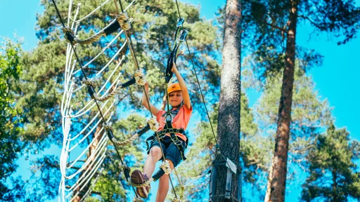 Nuori kiipeilee Pajulahden Seikkailupuiston puussa roikkuvalla radalla
