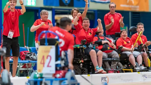 Sähköpyörätuoli salibandyn pelaaja ja joukkue taustalla tuulettaa maalia 