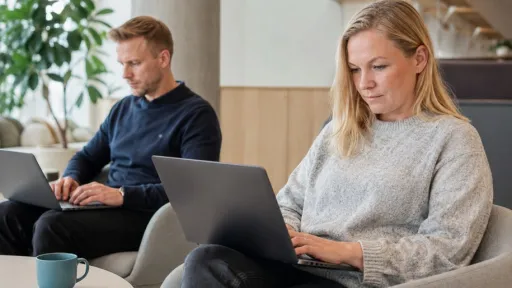 Mies ja nainen istuvat tuoleissaan, heillä on kannettavat tietokoneet syleissään