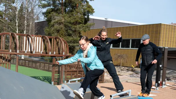 Kolme ihmistä esteradalla ulkona aurinkoisena päivänä.