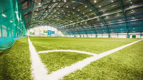 Indoor soccer field with artificial turf and overhead lighting.
