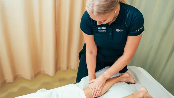 Hieroja hieroo asiakkaan jalkaa hoitohuoneessa.