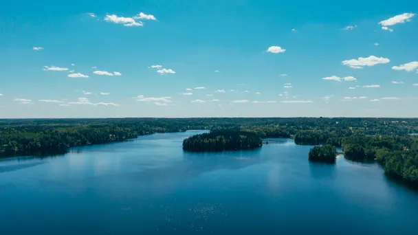 Aerial view of a calm blue lake under a clear sky with scattered small clouds.