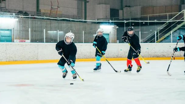 Jääkiekkoilijat pelaavat jääkiekkokaukalossa.