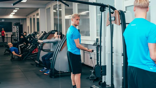 Mies treenaa kuntosalilla peilin edessä.