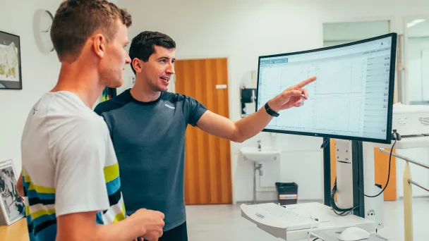 Kaksi miestä keskustelemassa tietokoneen näytön edessä.