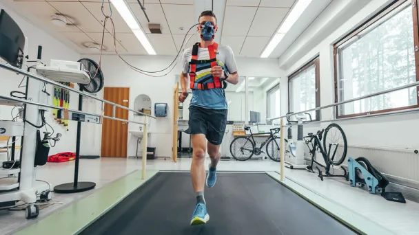 Juokseva henkilö hengitysmaski kasvoillaan laboratoriossa.