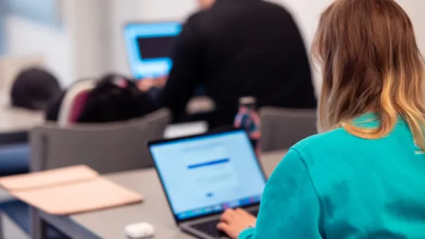 Nainen työskentelee kannettavalla tietokoneella luokassa.