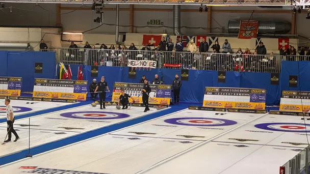 Curling-kilpailu sisätiloissa, useita kenttiä, katsomossa yleisöä.