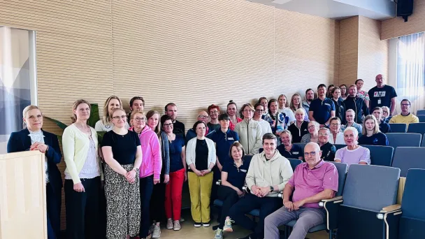 Ihmisiä seisomassa ja istumassa luentosalissa.